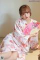 a woman in a kimono sitting on the floor holding a fan