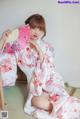 A woman in a kimono sitting on the floor holding a fan.