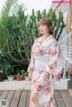 A woman in a white kimono standing on a wooden deck.