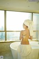 A woman with a towel wrapped around her back in a bathtub.