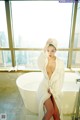 A woman in a white robe sitting in a bathtub.