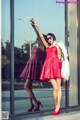 A woman in a red dress and a white fur coat posing for a picture.