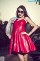 A woman in a red dress and sunglasses posing for a picture.