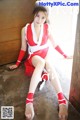 A woman in a red and white outfit sitting on the floor.