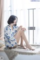 A woman sitting on a window sill with her legs crossed.