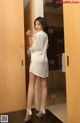 A woman in a white shirt and high heels standing in a bathroom.