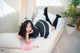 A woman laying on top of a bed next to a plant.