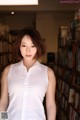 A woman standing in front of a bookshelf in a library.