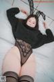 a woman laying on top of a bed wearing a black sweater and stockings