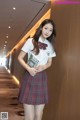 A woman in a school uniform holding a book.