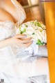 A woman in a wedding dress holding a bouquet of flowers.