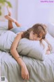 A woman laying on top of a bed with a pillow.