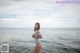 A woman in a striped bathing suit standing in the water.