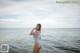 A woman in a striped bathing suit standing in the water.