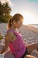 A woman in a pink tank top sitting on a beach.