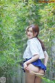 A woman in a white shirt and blue skirt posing in a bamboo forest.