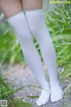 A close up of a person wearing white stockings in the grass.