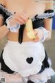 A woman in a maid outfit holding a banana.