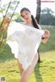 A woman in a white lingerie posing in a field.