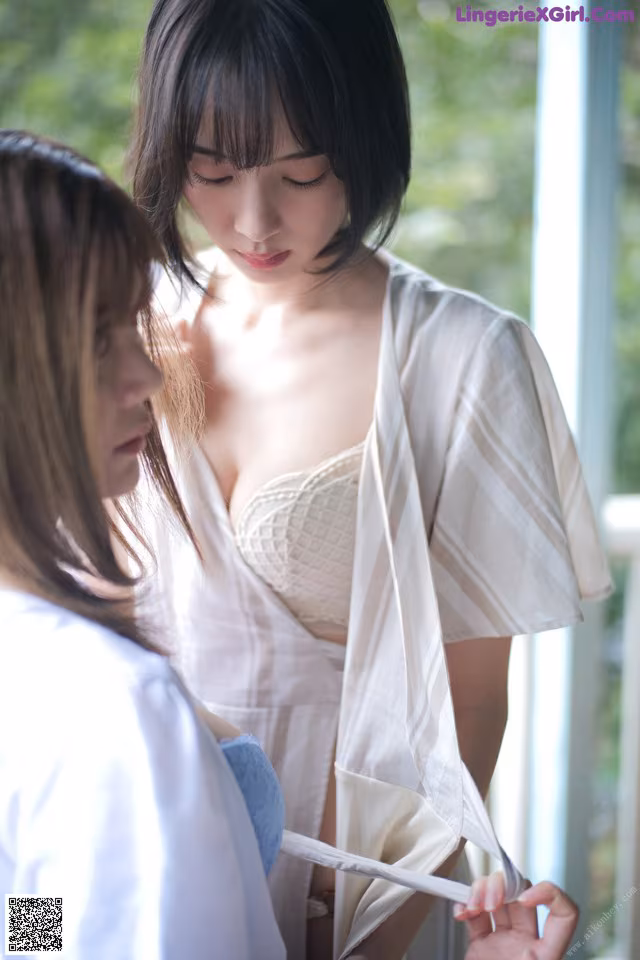 A woman in a white robe is putting on a bra.