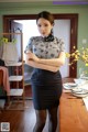 A woman standing in front of a table with her arms crossed.