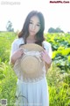 A woman in a white dress holding a straw hat.