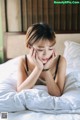 A woman laying on a bed with her hand on her face.