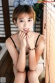 A young woman sitting on a wooden bench with her hands on her chin.