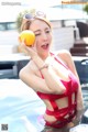 A woman in a red bikini holding an orange in a pool.